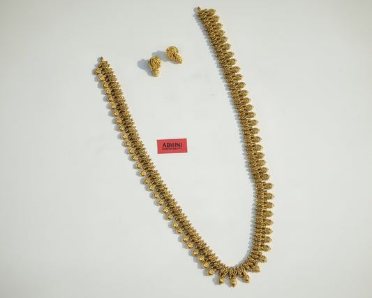 Gold necklace and earrings on a pink and white fabric with 'ABHINI JEWELS' branding.