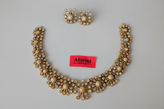 Gold necklace and earrings with 'ABHINI JEWELS' label on a white background
