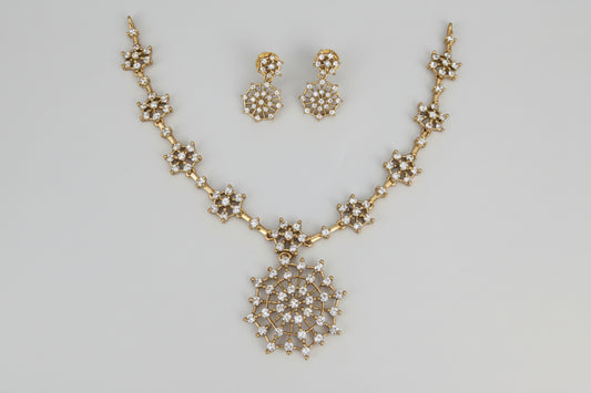 Gold necklace and earrings set on a white background